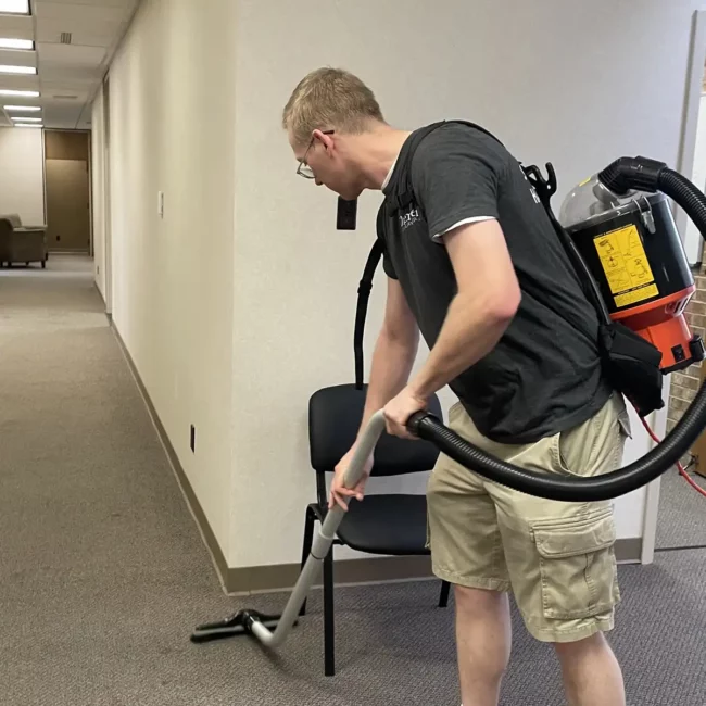 Premier Cleaning, LLC employee vacuuming office floor